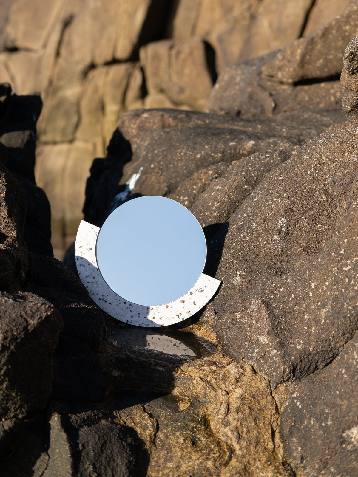Miroir noir en coquillages recyclés sur un sol en parquet